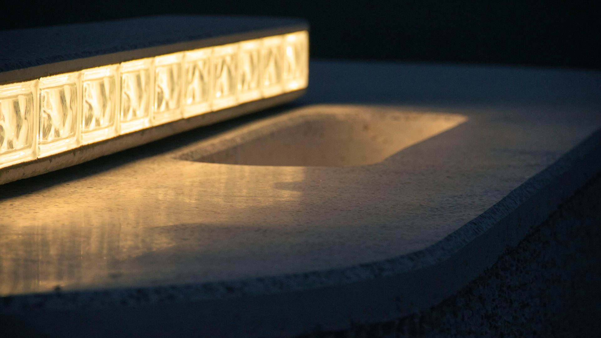 Lit glass-block strip set into a cast concrete counter at dusk