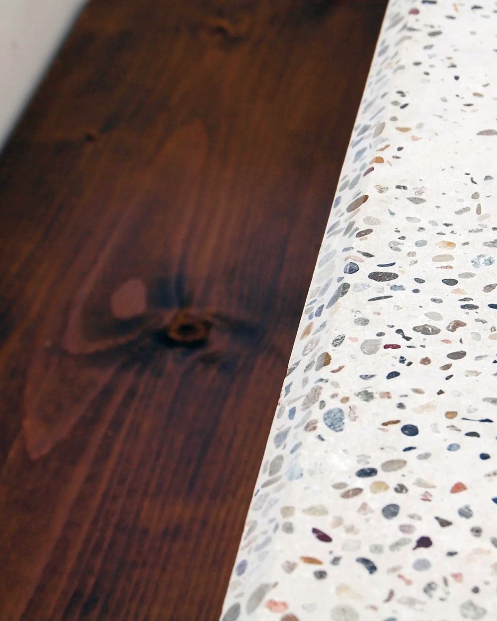 Oiled walnut inlay meeting the polished terrazzo top