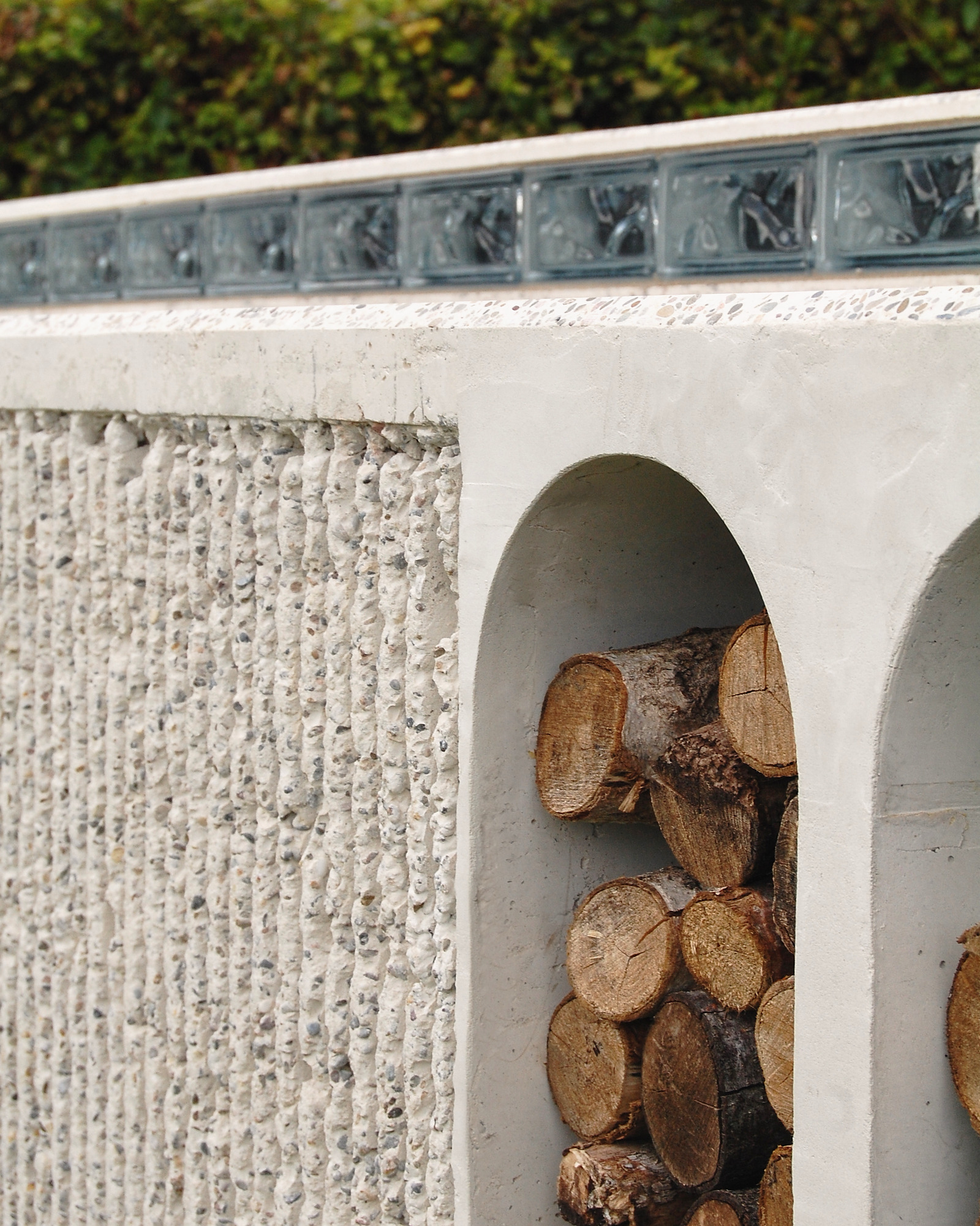 Close-up of hand-chipped cast concrete with glass-block band and firewood niche