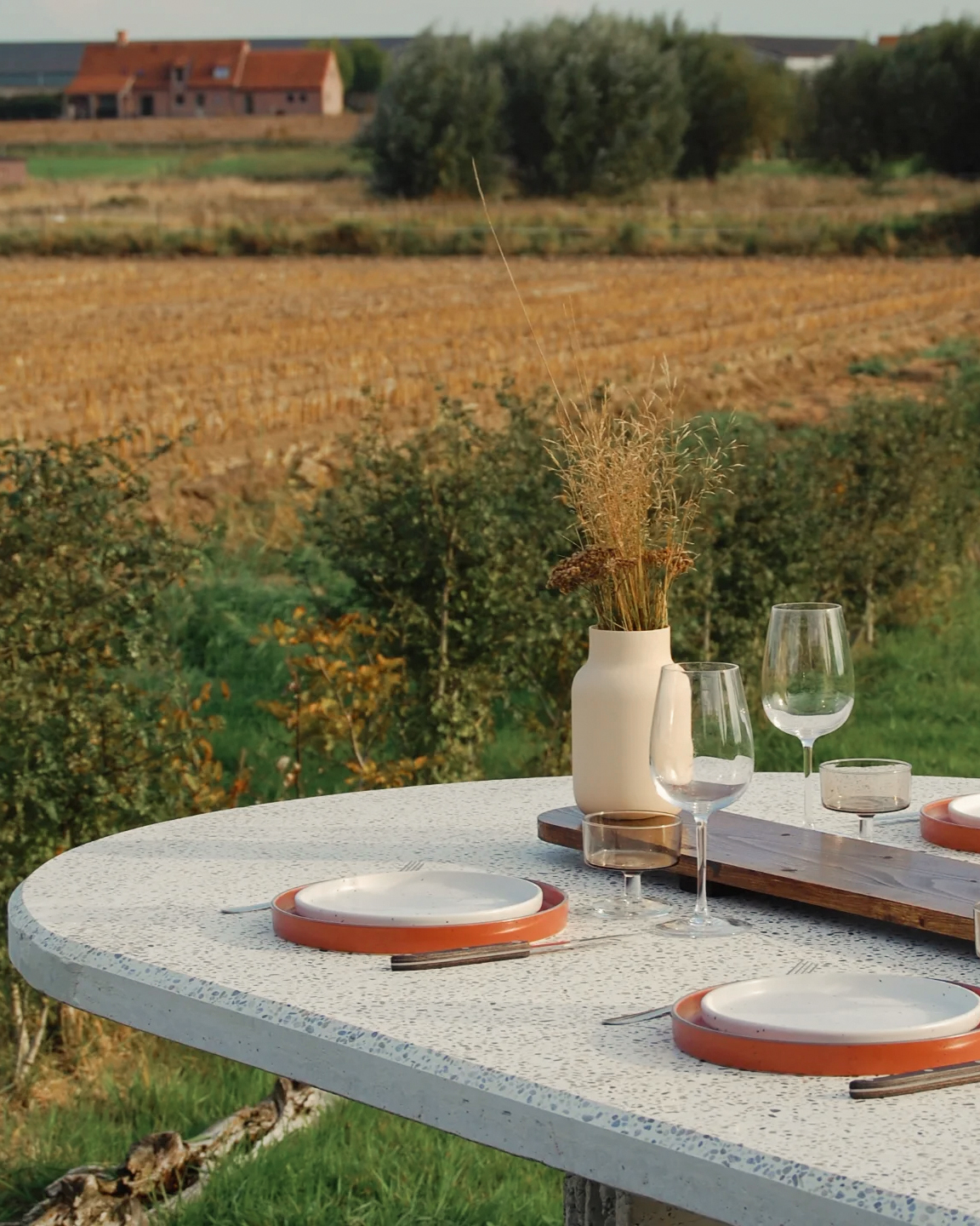 Terrazzo table set for a meal overlooking the open West Flanders fields